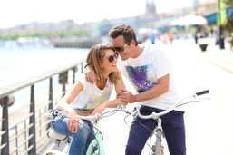 Cheerful couple riding bikes by sunny day